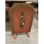 A VINTAGE WOODEN AND BASKET WEAVE FIRE SCREEN, RED WITH FLORAL DECORATION