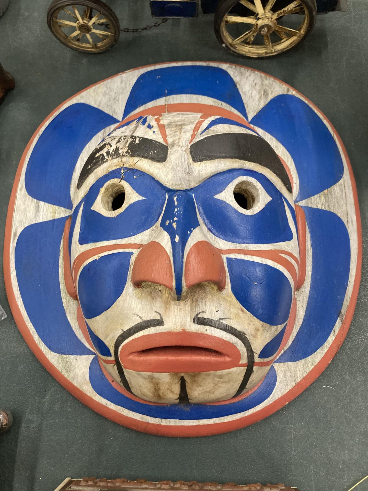 A CARVED WOODEN FACE MASK WITH RED, WHITE AND BLUE DESIGN