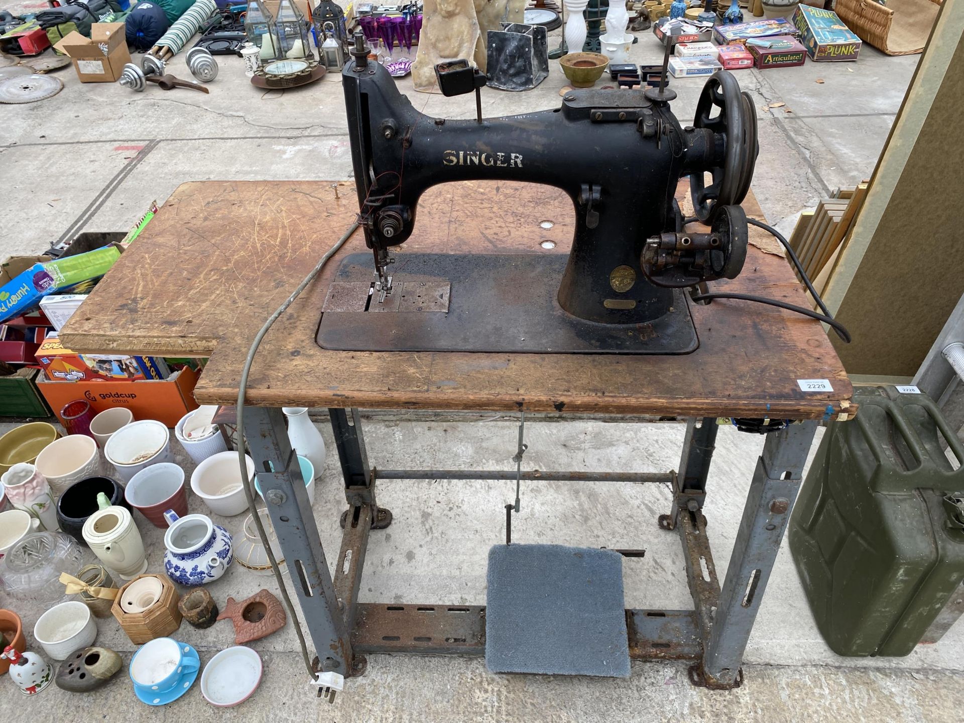 AN INDUSTRIAL SINGER SEWING MACHINE WITH TREADLE BASE