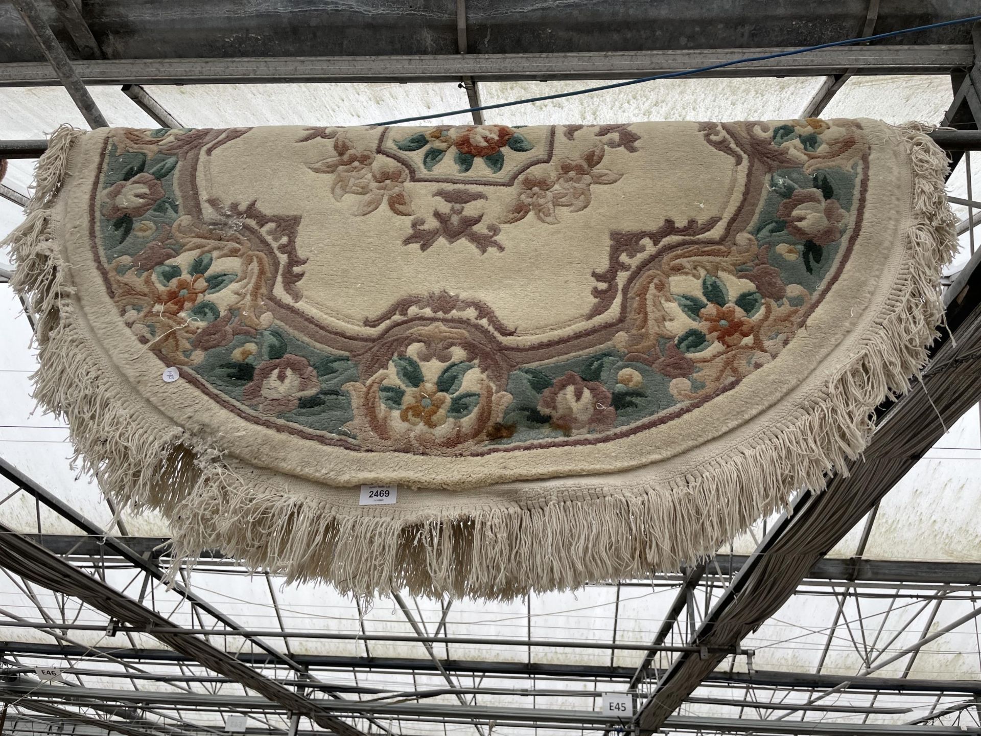 A CREAM PATTERNED OVAL FRINGED RUG