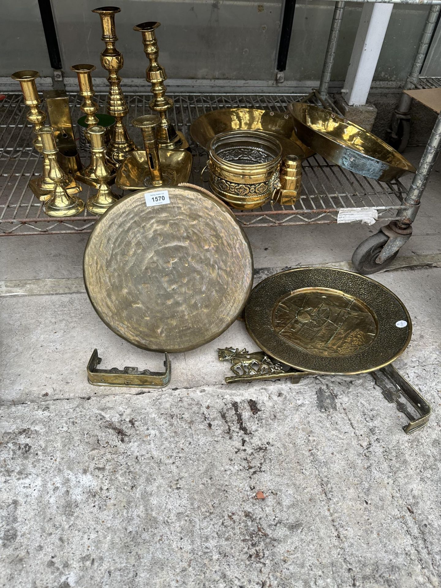 A LARGE ASSORTMENT OF BRASS ITEMS TO INCLUDE PANS, CHARGERS,A GONG AND CANDLE STICKS ETC