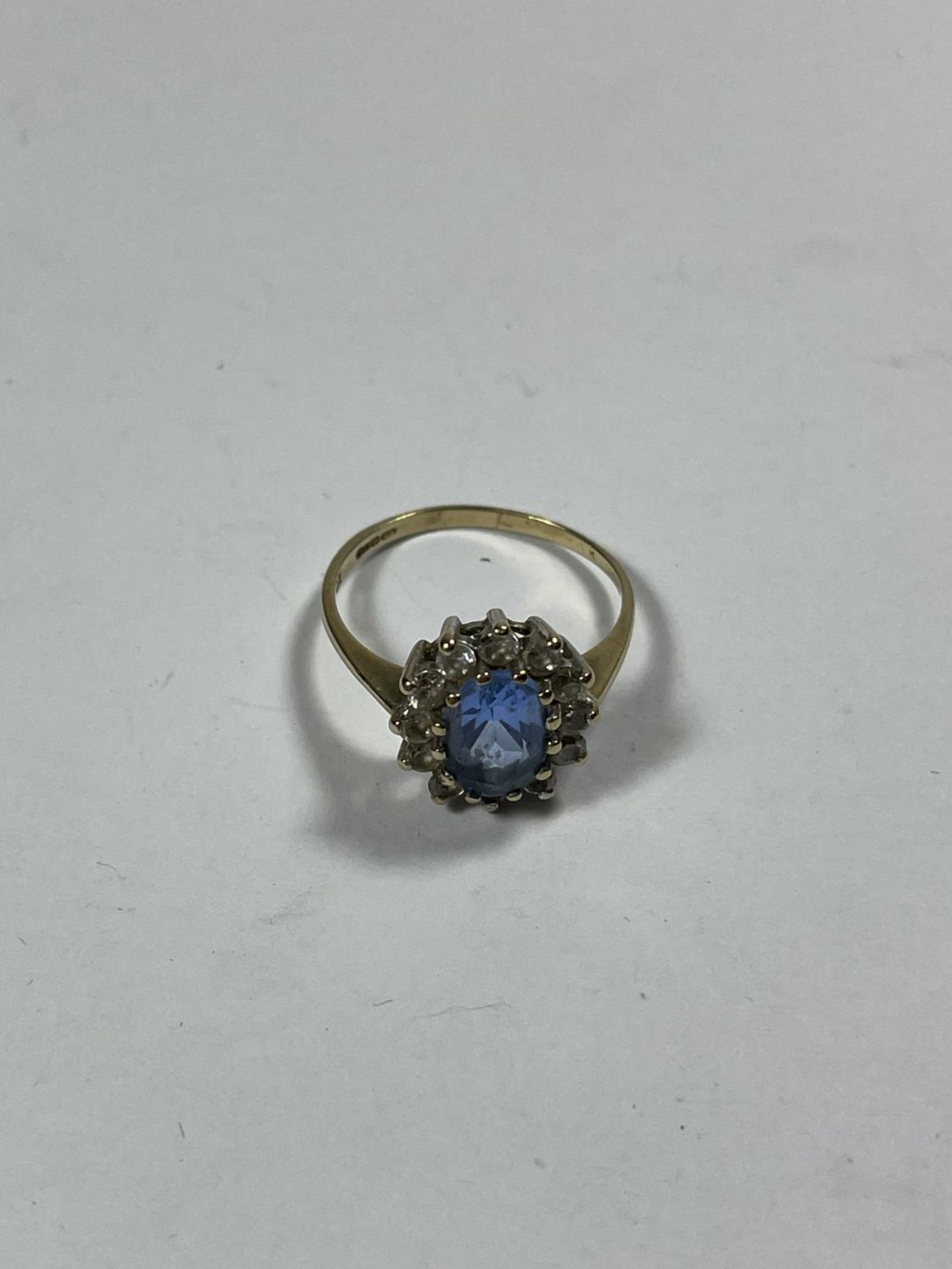 A 9 CARAT GOLD RING WITH A CENTRE TOPAZ SURROUNDED BY TWELVE CUBIC ZIRCONIAS SIZE N/O