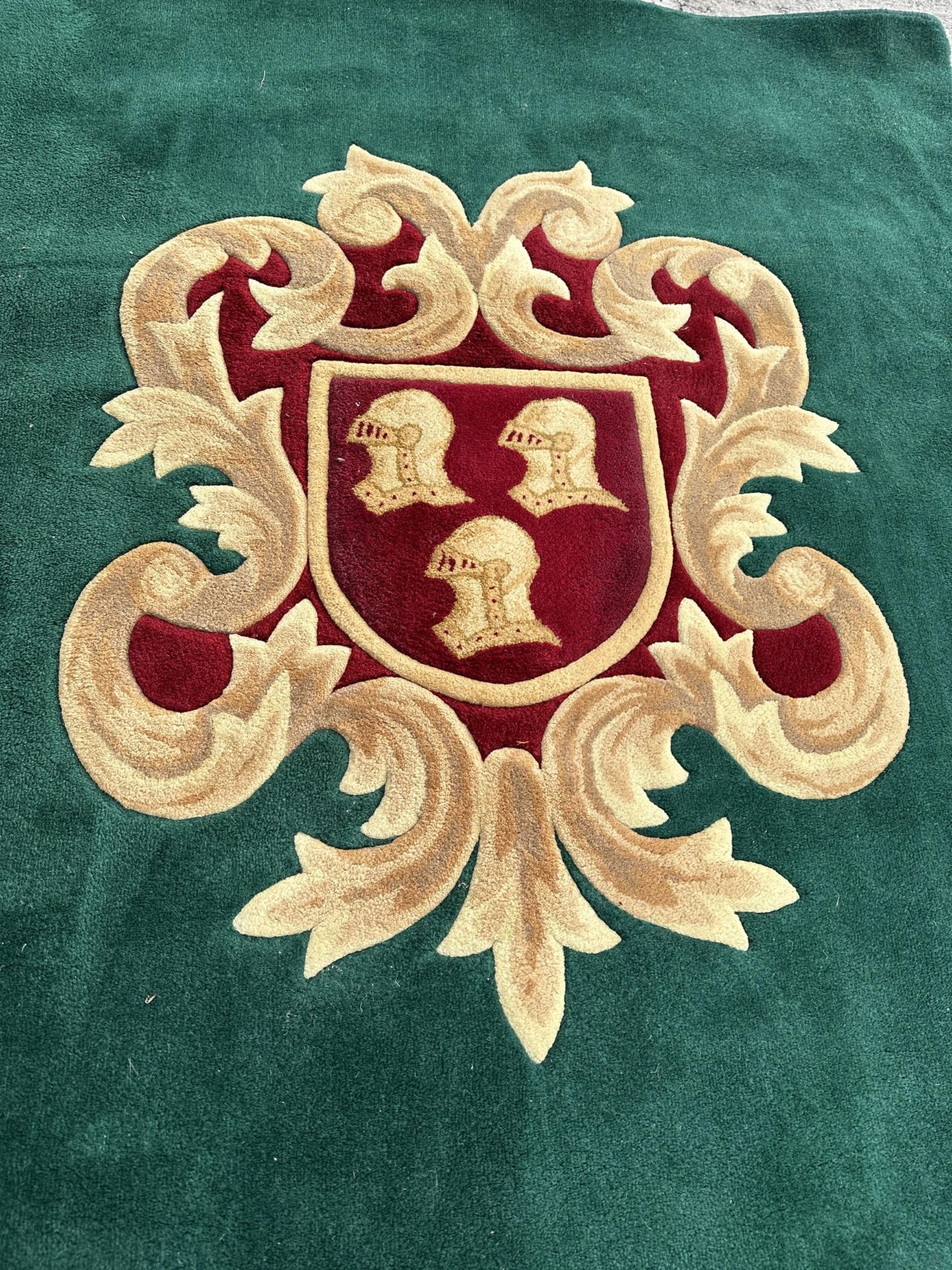 A GREEN AND RED PURE WOOL RUG WITH ARMORIAL CREST - INCLUDES SEVEN MATCHING CURTAIN TIE BACKS - - Image 2 of 6