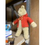 A SOFT TOY TEDDY BEAR IN A RED JACKET