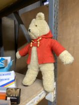 A SOFT TOY TEDDY BEAR IN A RED JACKET