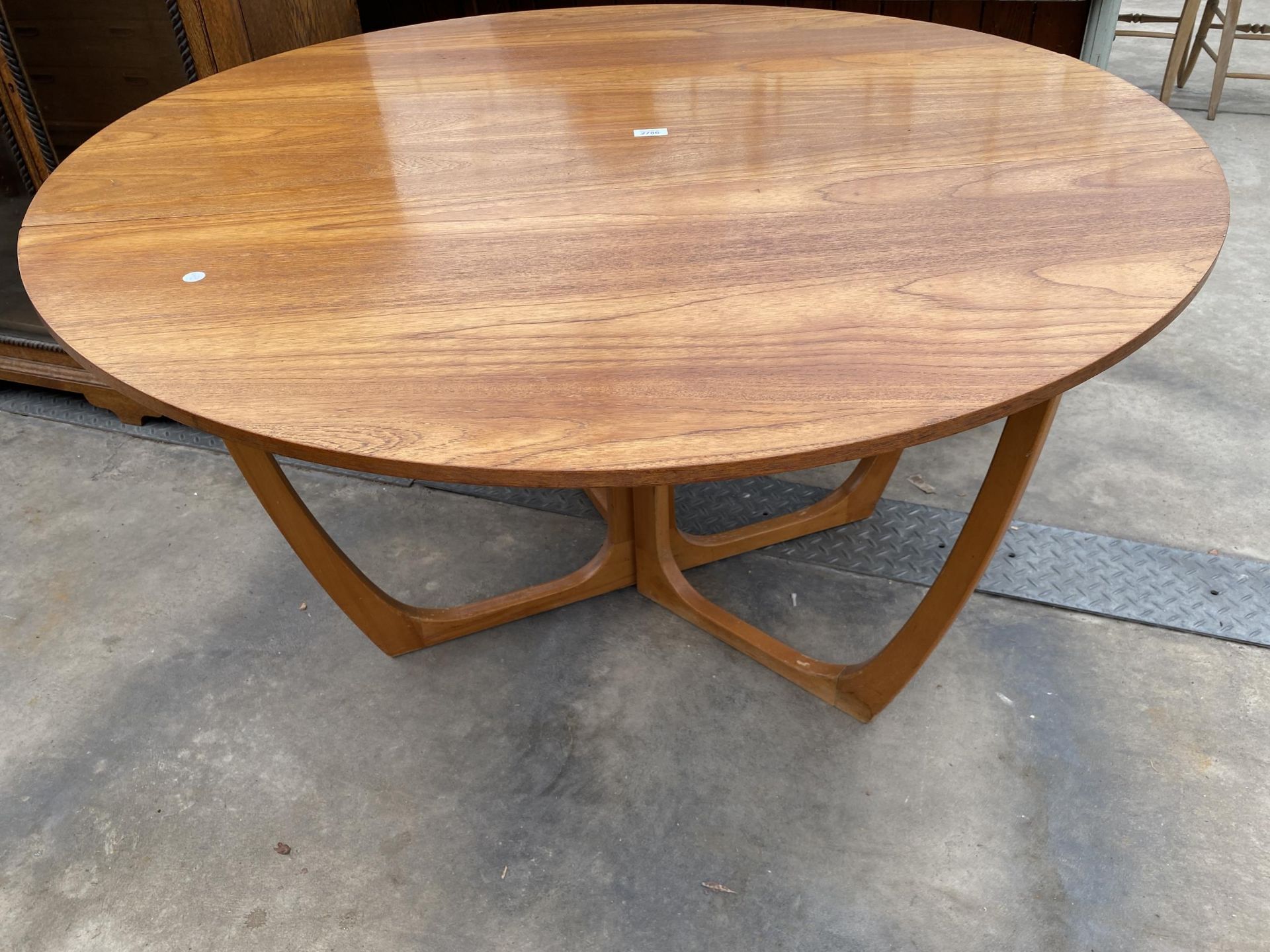 A RETRO TEAK 50" DIAMETER CROSS-FRAME GATELEG DINING TABLE