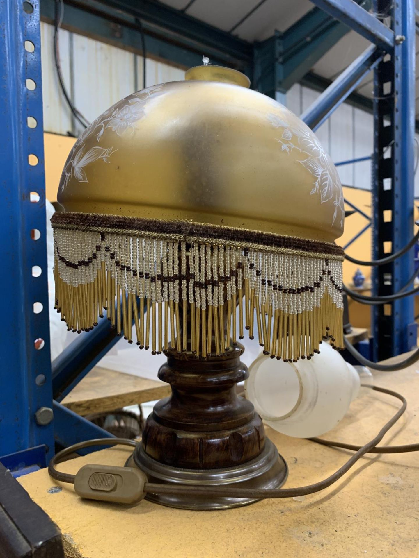 A VINTAGE TABLE LAMP WITH CARVED WOODEN BASE AND A GLASS LAMP SHADE WITH BEADING