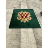 A GREEN AND RED PURE WOOL RUG WITH ARMORIAL CREST - INCLUDES SEVEN MATCHING CURTAIN TIE BACKS -