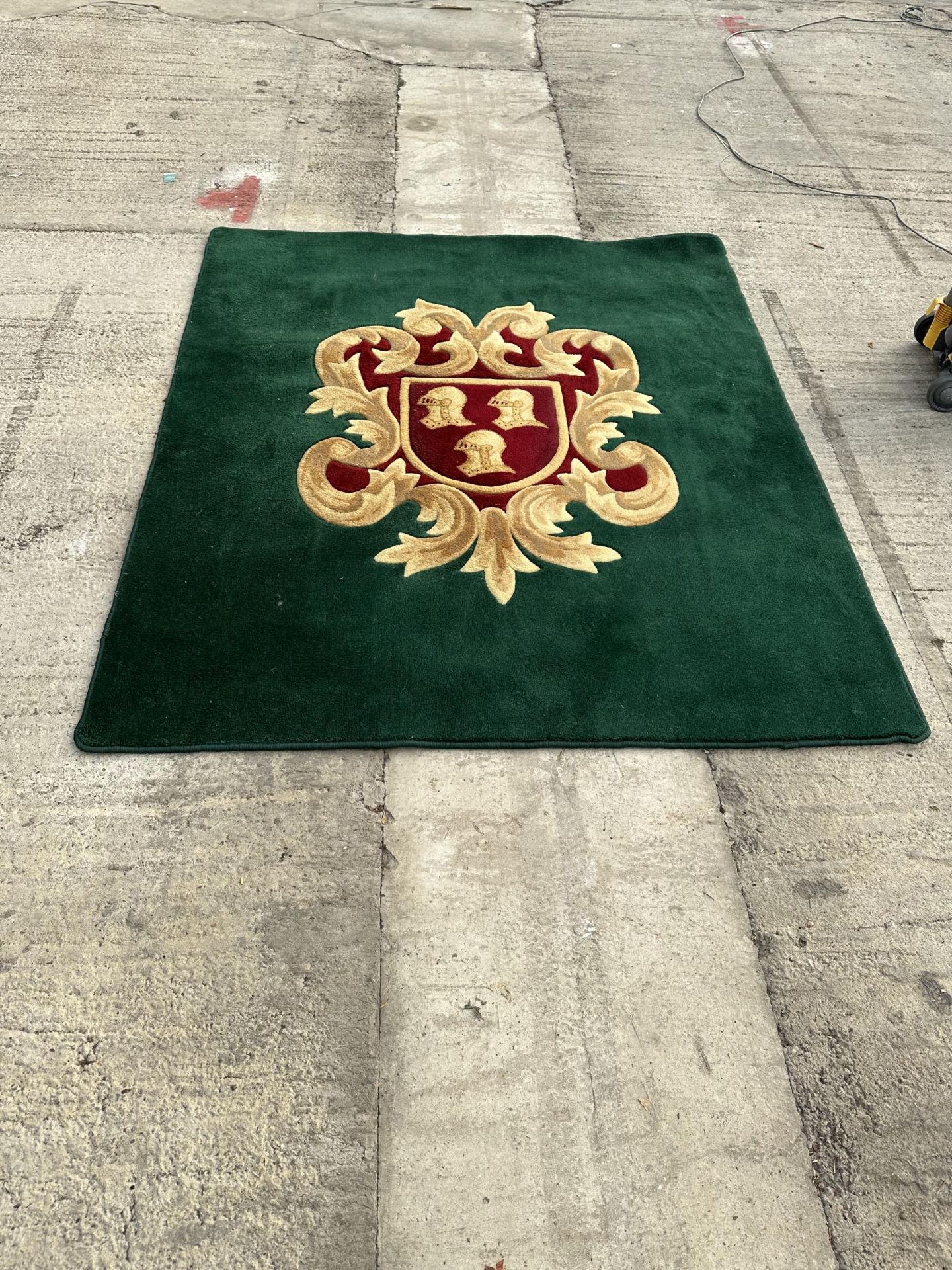 A GREEN AND RED PURE WOOL RUG WITH ARMORIAL CREST - INCLUDES SEVEN MATCHING CURTAIN TIE BACKS -