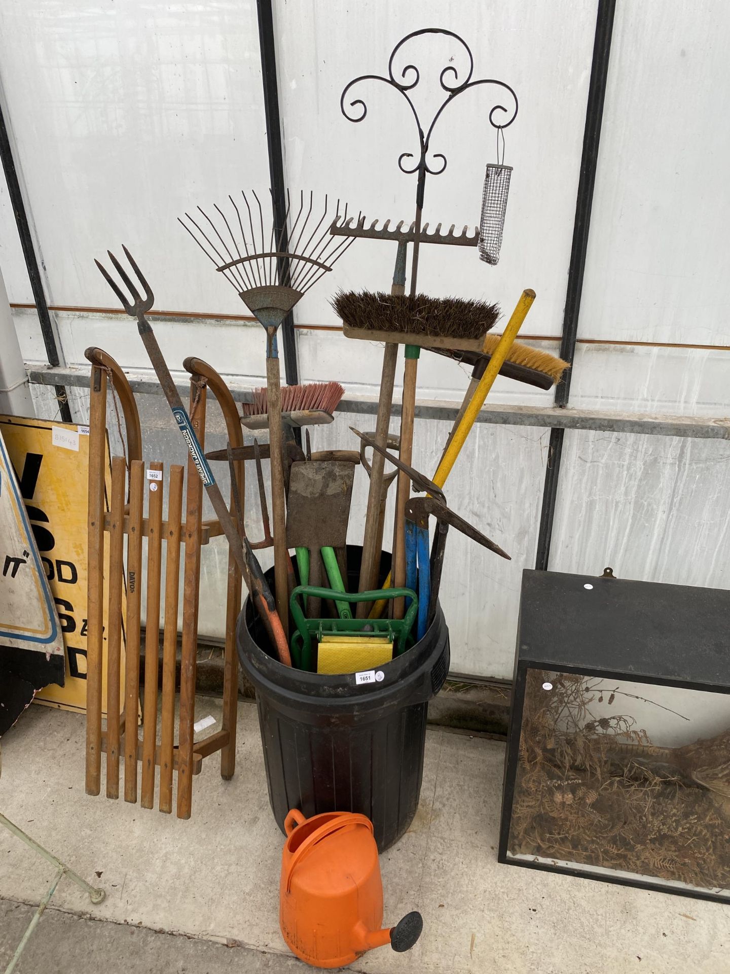 A DUSTBIN CONTAINING AN ASSORTMENT OF GARDEN TOOLS TO INCLUDE FORK, SPADE, RAKES AND BRUSHES ETC