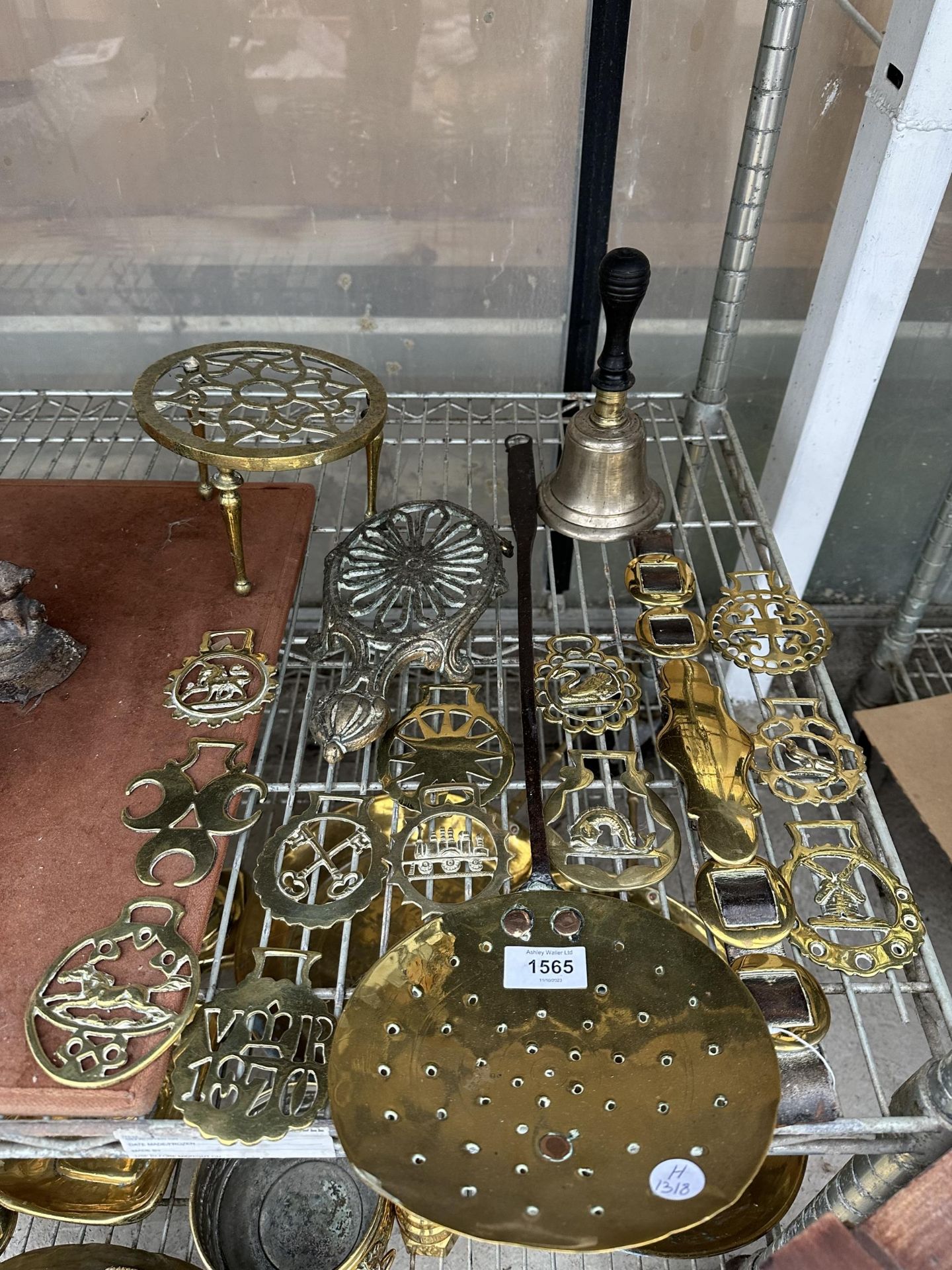 AN ASSORTMENT OF VINTAGE BRASS WARE TO INCLUDE A TRIVET STAND, HORSE BRASSES AND A BELL ETC