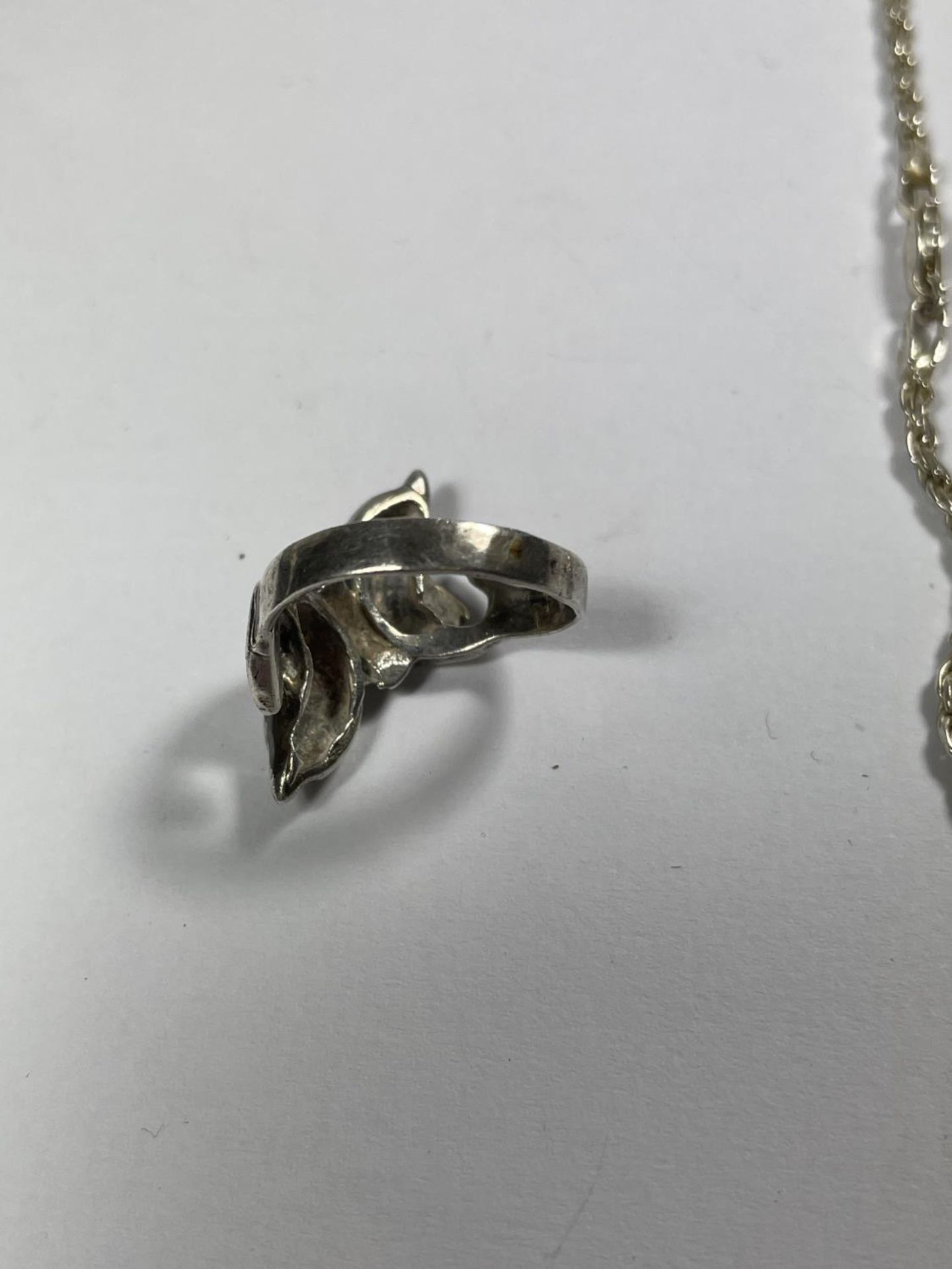 A SILVER NECKLACE WITH A DOUBLE DOLPHIN AND CLEAR STONE PENDANT AND A DOUBLE DOLPHIN RING IN A - Image 5 of 5
