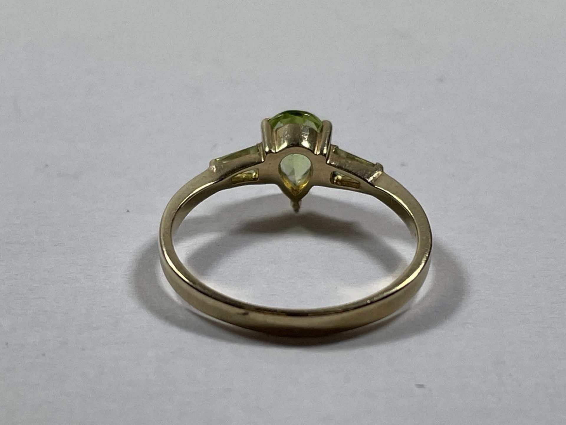 A 9 CARAT GOLD RING WITH A TEARDROP PERIDOT STONE AND ONE TO EACH SHOULDER SIZE P - Image 2 of 3