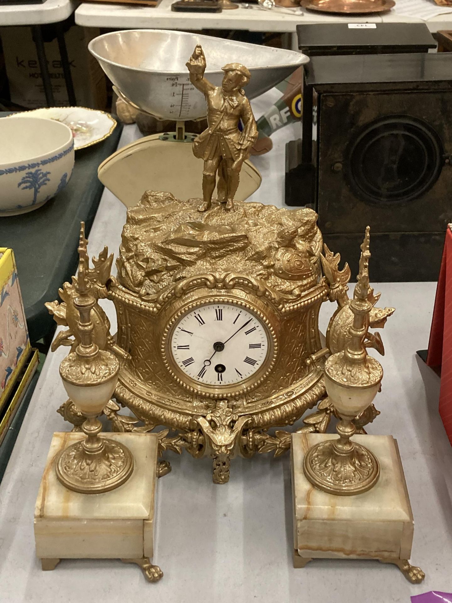 A FRENCH STYLE GILT EFFECT ORNATE MANTLE CLOCK AND ONYX GARNITURE SET WITH FIGURAL TOP