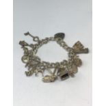 A SILVER CHARM BRACELET WITH FIFTEEN CHARMS AND A HEART PADLOCK