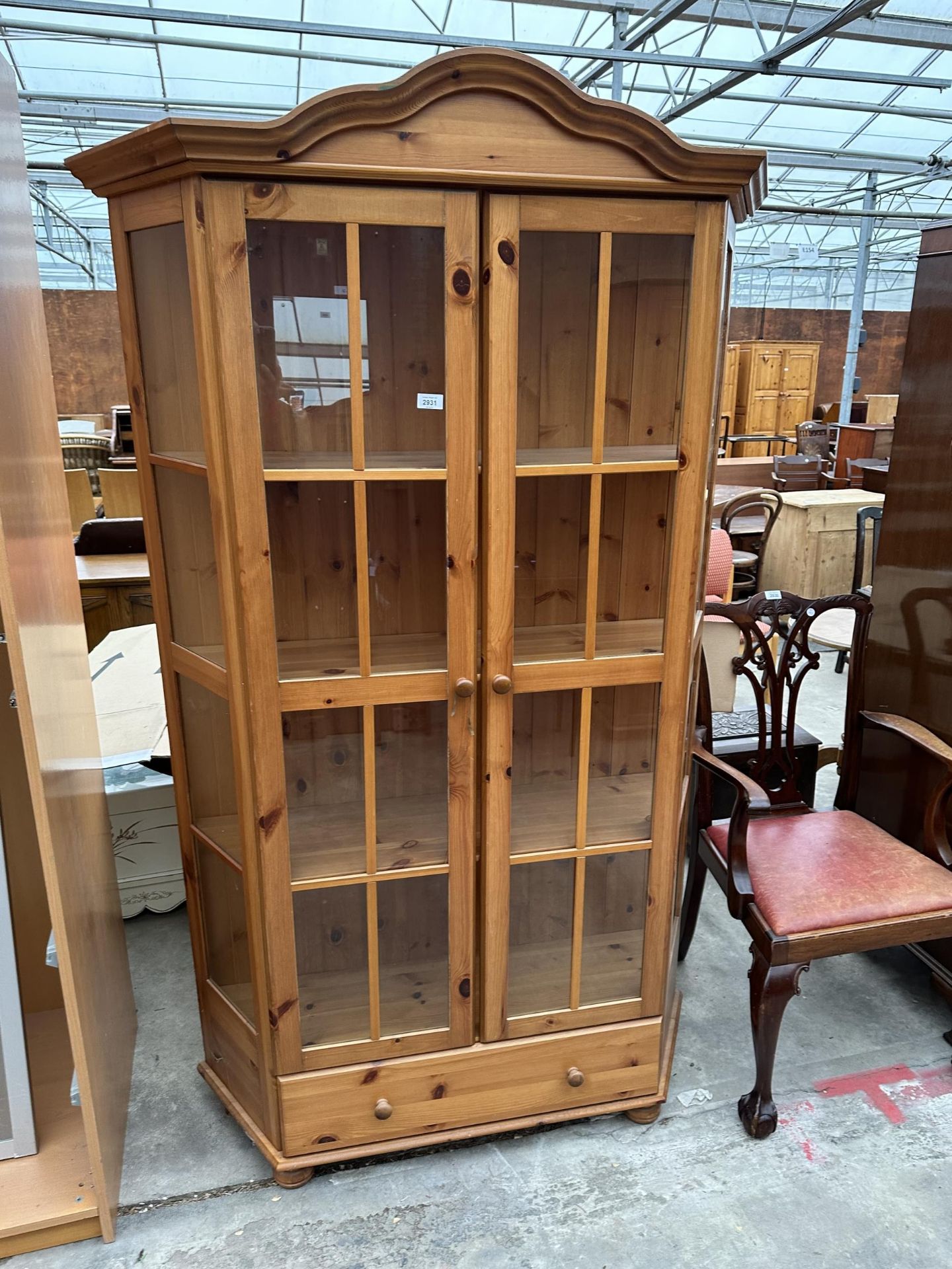 A MODERN PINE GLAZED TWO DOOR DISPLAY CABINET WITH DRAWER TO THE BASE, 48" WIDE