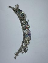 A SILVER CHARM BRACELET WITH TWENTY FOUR VARIOUS CHARMS WEIGHT 48.2 GRAMS