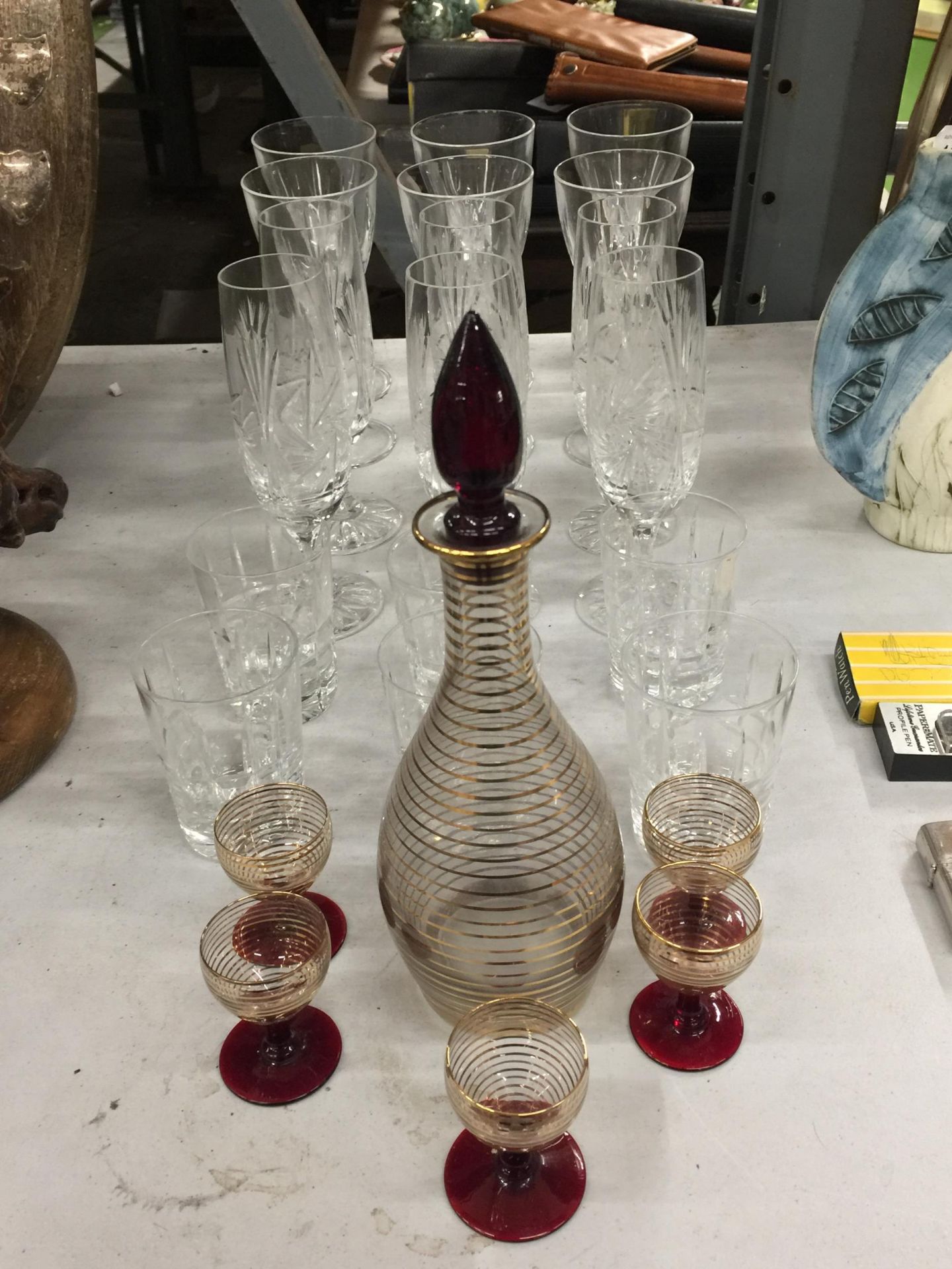 A GROUP OF CUT GLASS CHAMPAGNE FLUTES, CRANBERRY AND GILT DESIGN DECANTER AND FIVE GLASSES ETC