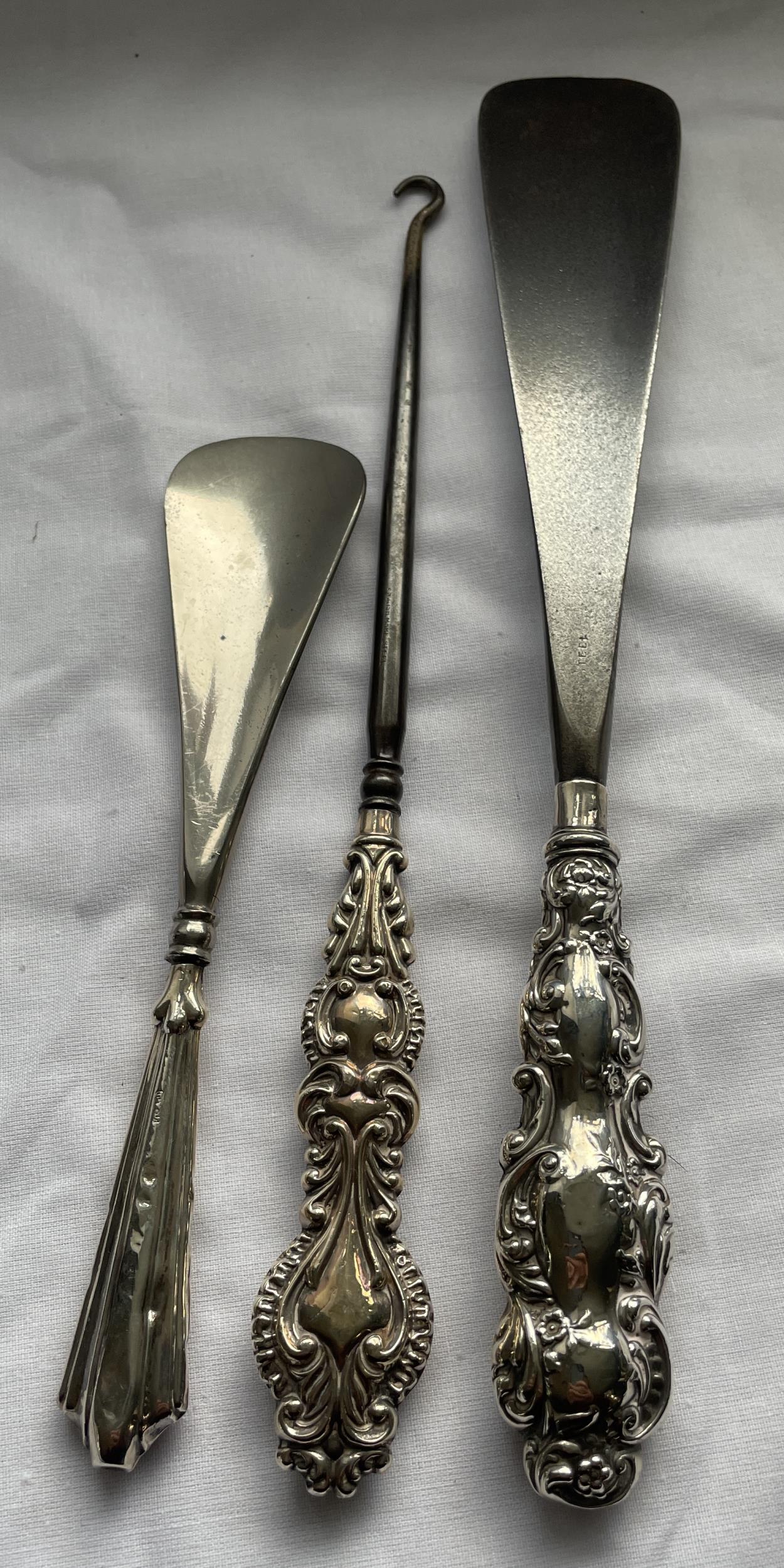 A SET OF THREE HALLMARKED SILVER HANDLED ITEMS - TWO SHOE HORNS AND BUTTON HOOK, GROSS WEIGHT 222