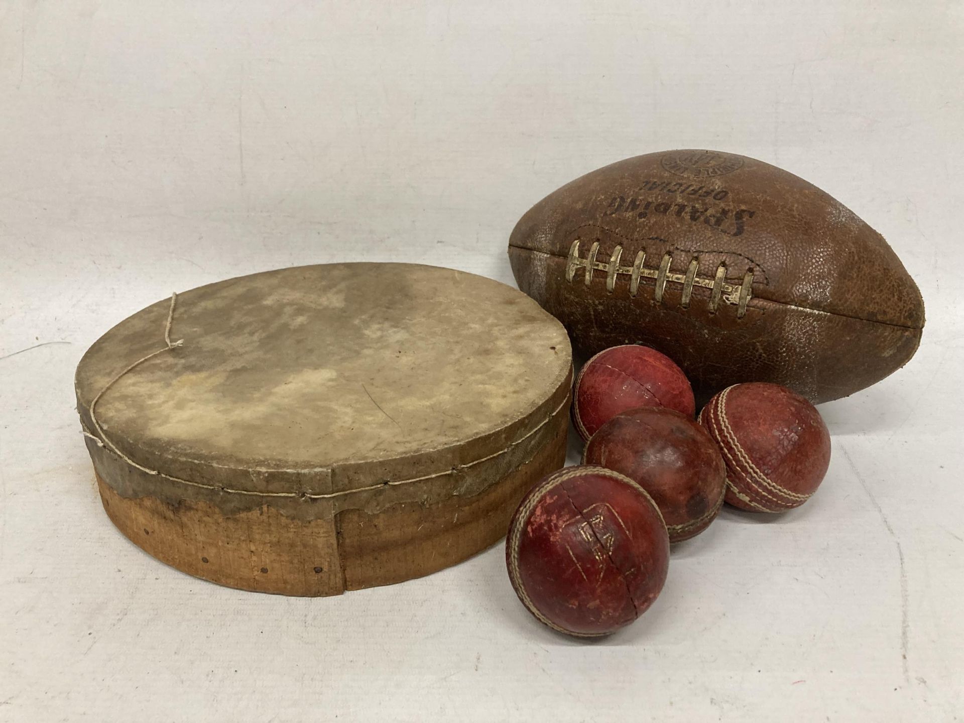 A COLLECTION OF VINTAGE SPORTING ITEMS, SPALDING RUGBY BALL, CRICKET BALLS AND A TAMBORINE