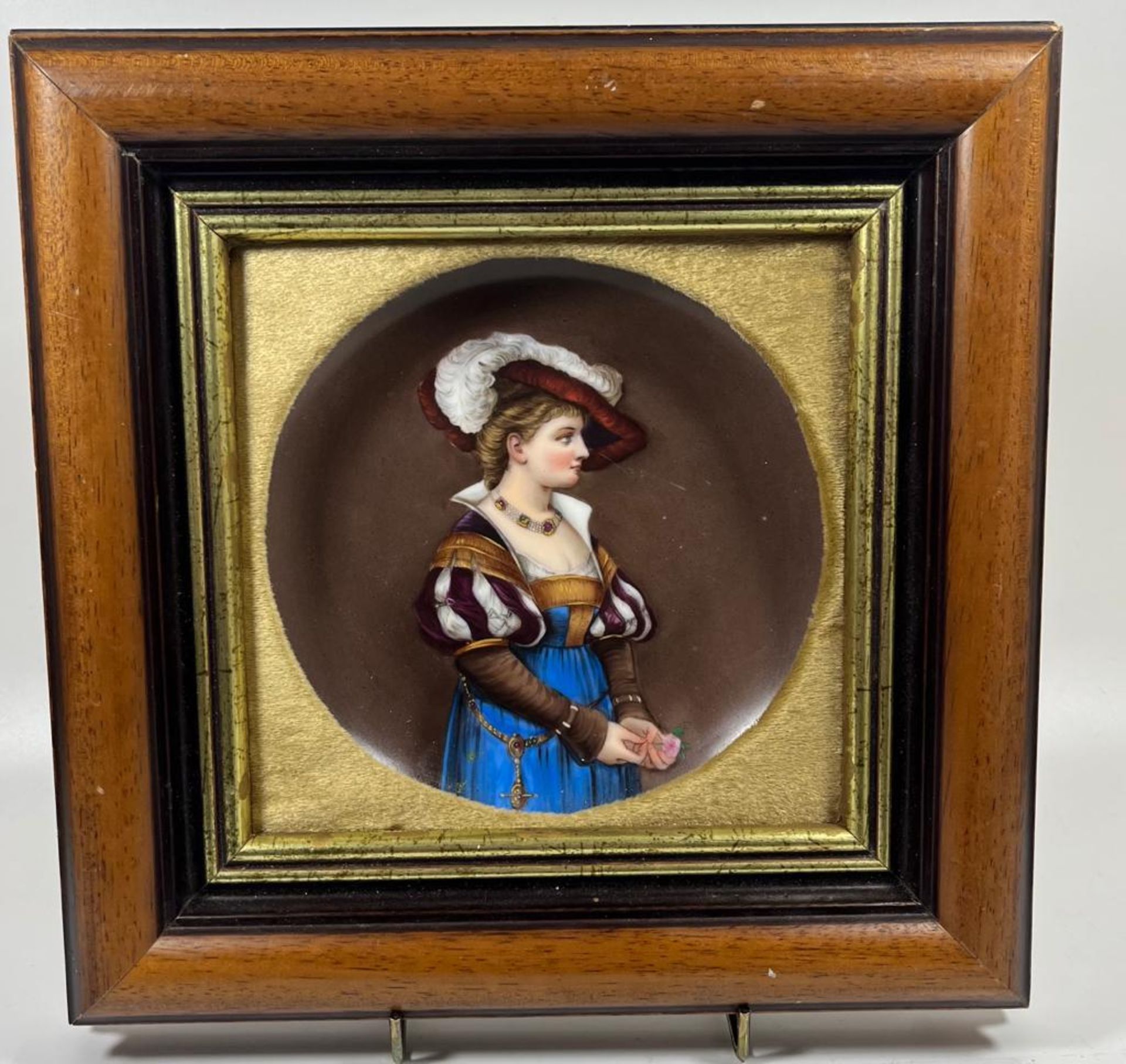 A 19TH CENTURY FRAMED HAND PAINTED PORCELAIN PLAQUE DEPICTING A LADY WITH A FEATHERED HAT, 27 X 26CM