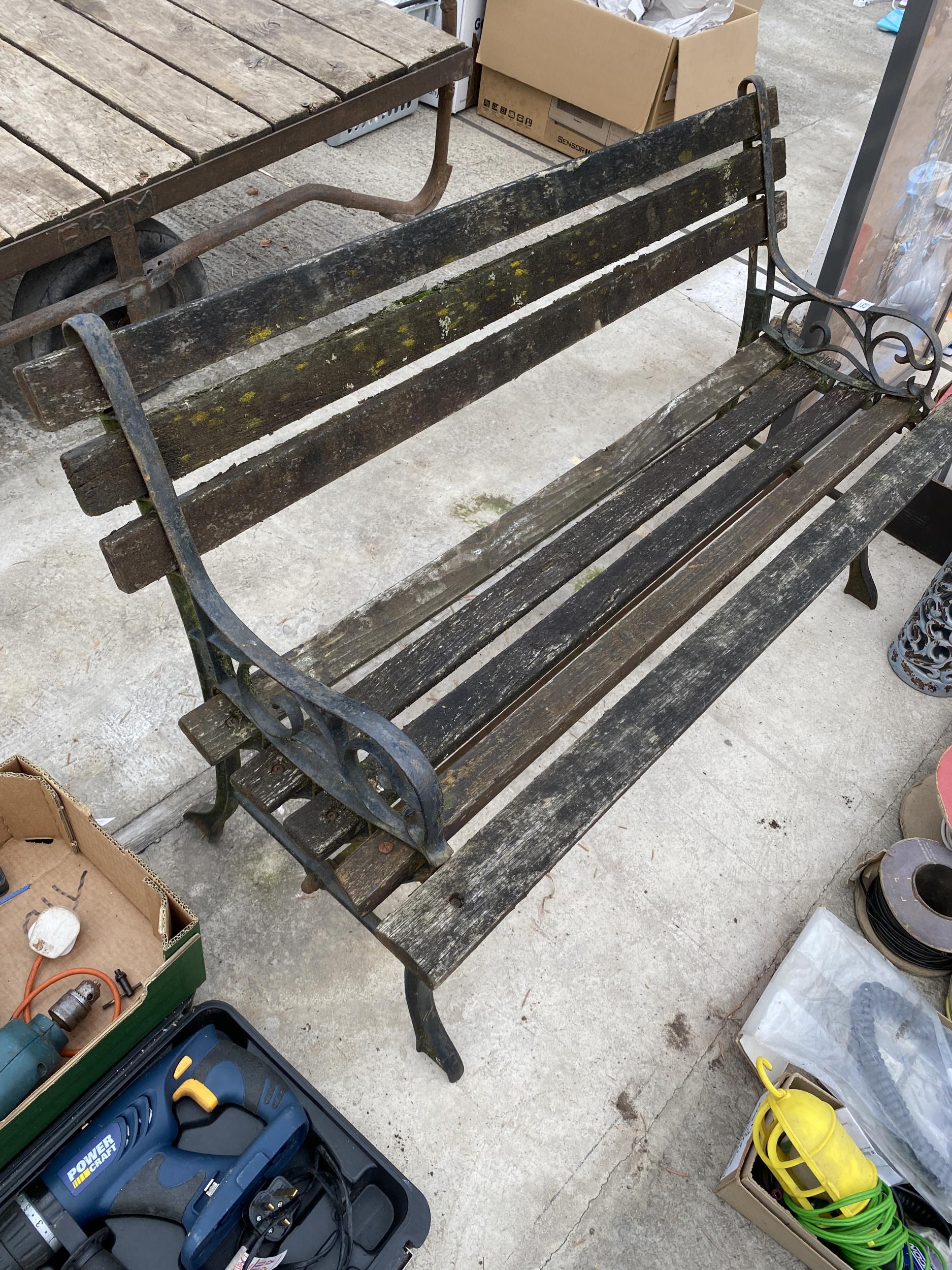 A WOODEN SLATTED GARDEN BENCH WITH CAST BENCH ENDS