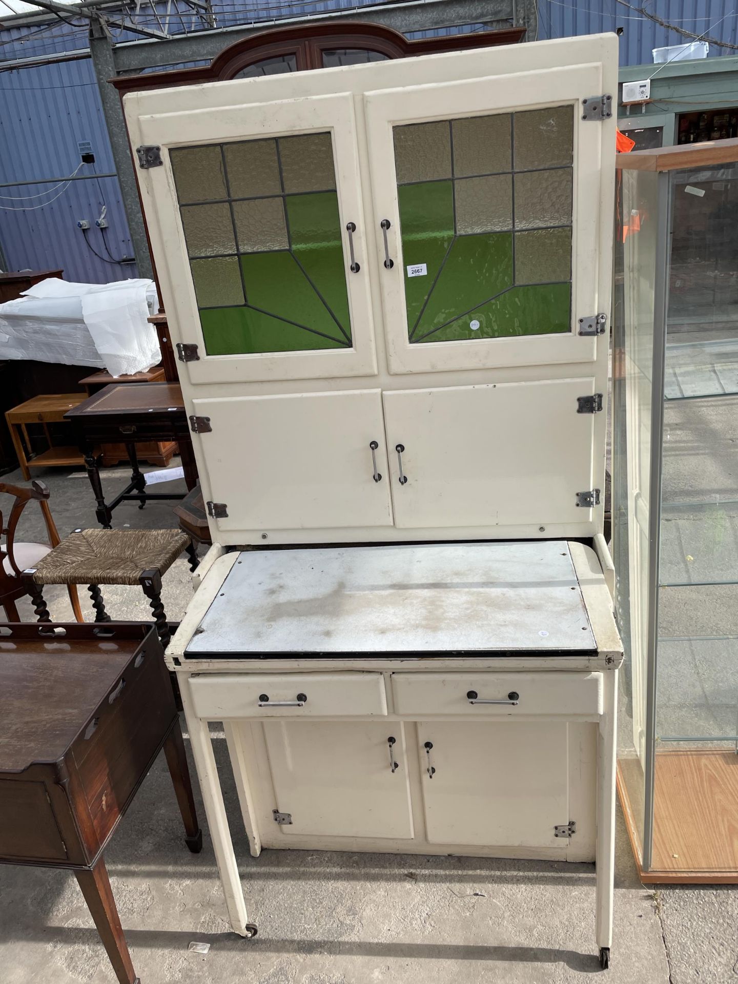 A 1950'S METALWARE KITCHEN CABINET WITH PULL-OUT ENAMEL WORK SURFACE, ON LEGS WITH CASTERS, WITH