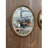 AN OVAL GILT FRAMED WALL MIRROR, 27 X 23"