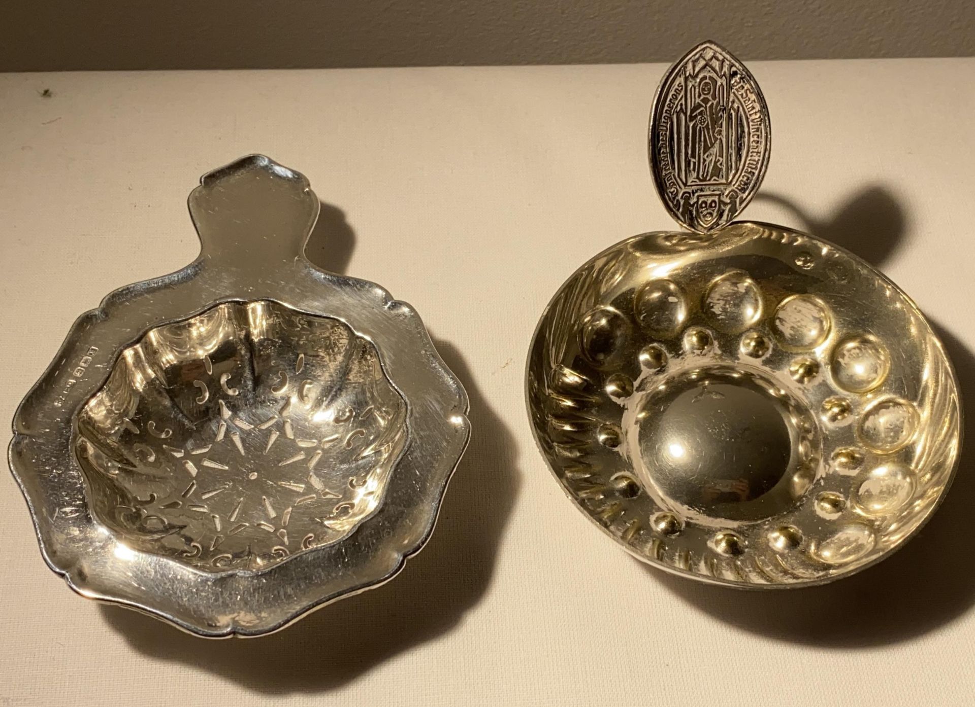 TWO ITEMS - A 1947 HALLMARKED BIRMINGHAM TEA STRAINER AND A WINE CUP MARKED WITH SAINT VINCENT