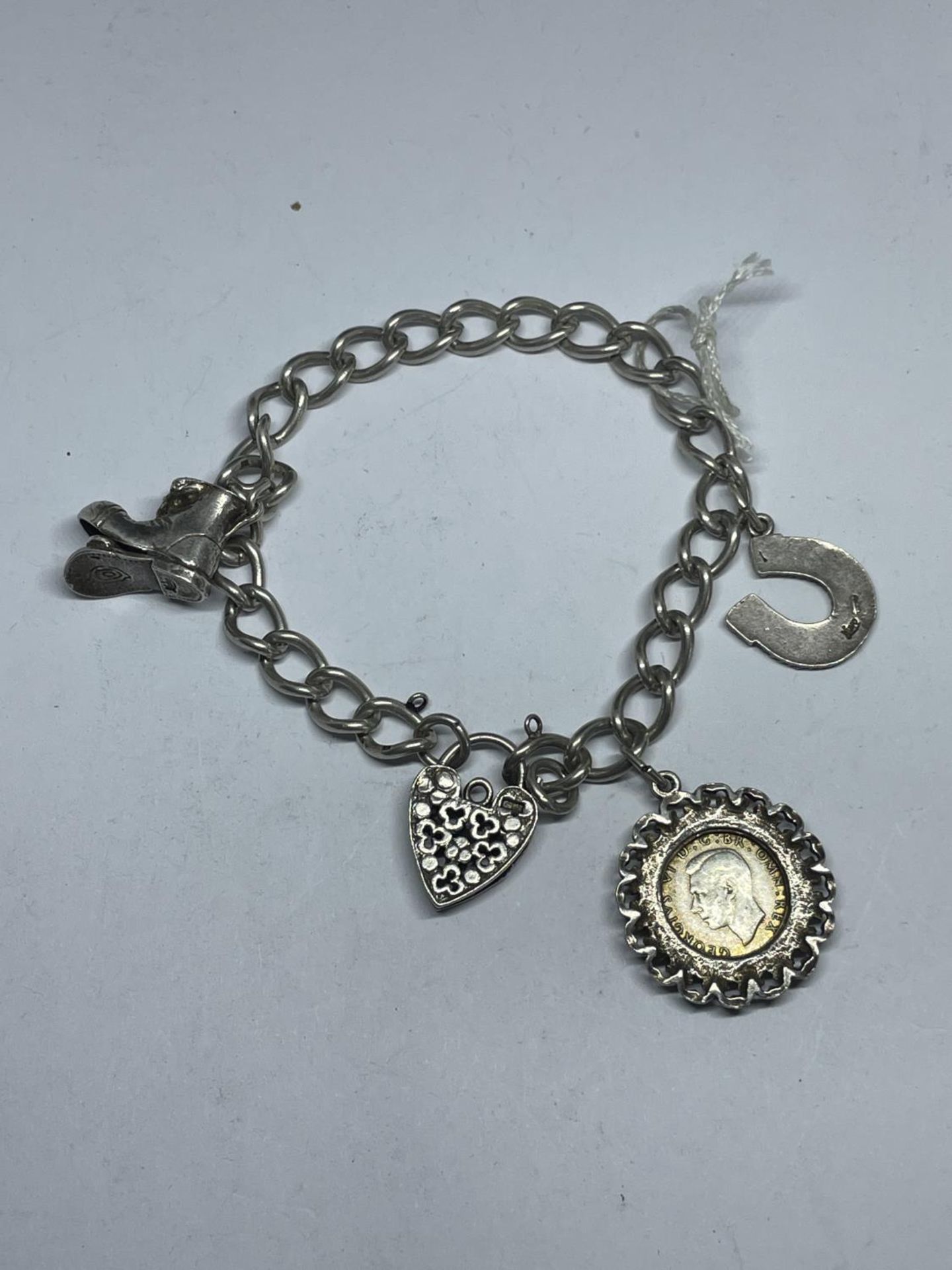 A SILVER CHARM BRACELET WITH THREE CHARMS AND A DECORATIVE HEART PADLOCK WEIGHT 25.5 GRAMS