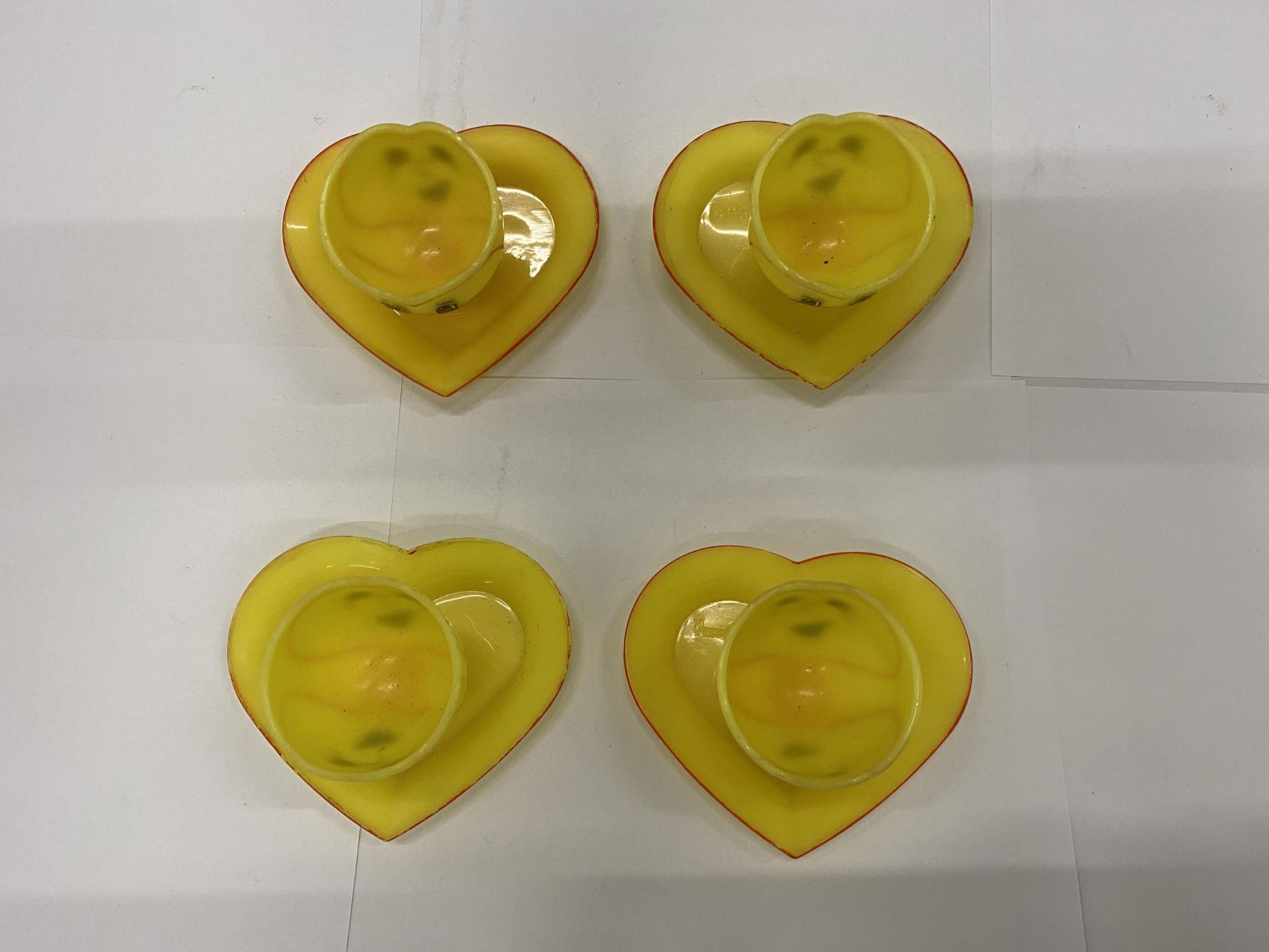 FOUR YELLOW PLASTIC EGGCUPS WITH HEART SHAPED SAUCERS AND FACES ON THE FRONT AND BACK - Image 3 of 3