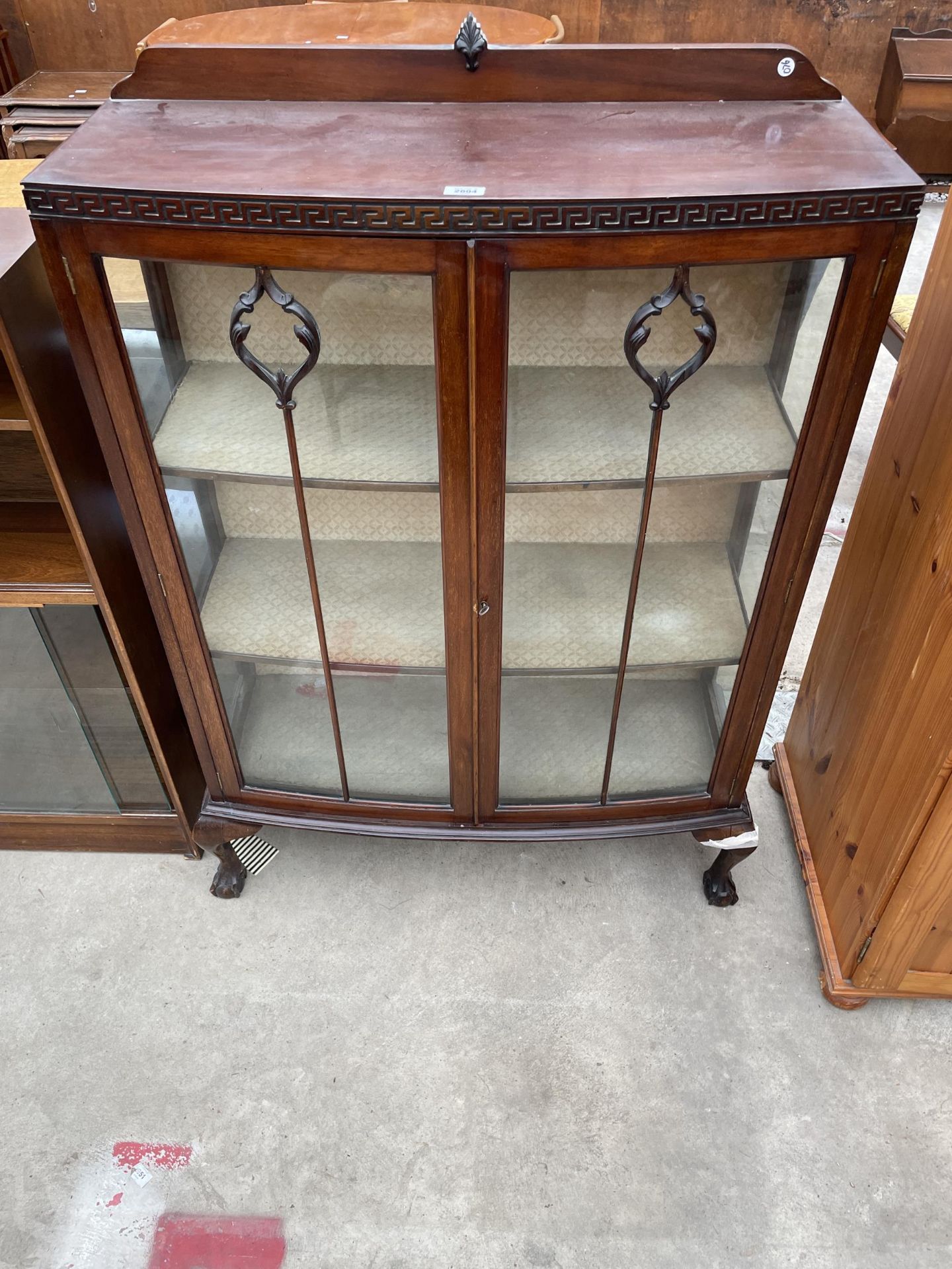 AN EARLY 20TH CENTURY MAHOGANY TWO DOOR GLASS DISPLAY CABINET WITH GREEK KEY CARVING, ON CABRIOLE