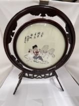 A CHINESE WOODEN FRAMED CIRCULAR PRINT OF A GIRL WITH GOATS