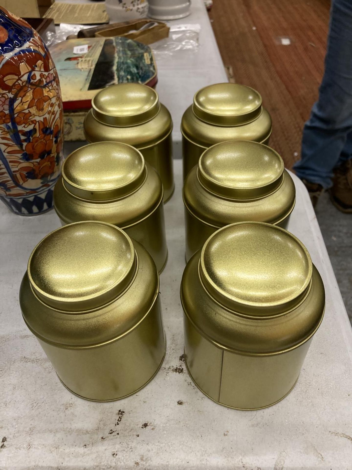 SIX GOLD COLOURED TEA CADDIES, ONE CONTAINING 'TEA FROM THE MANOR' CHRISTMAS BLEND TEABAGS