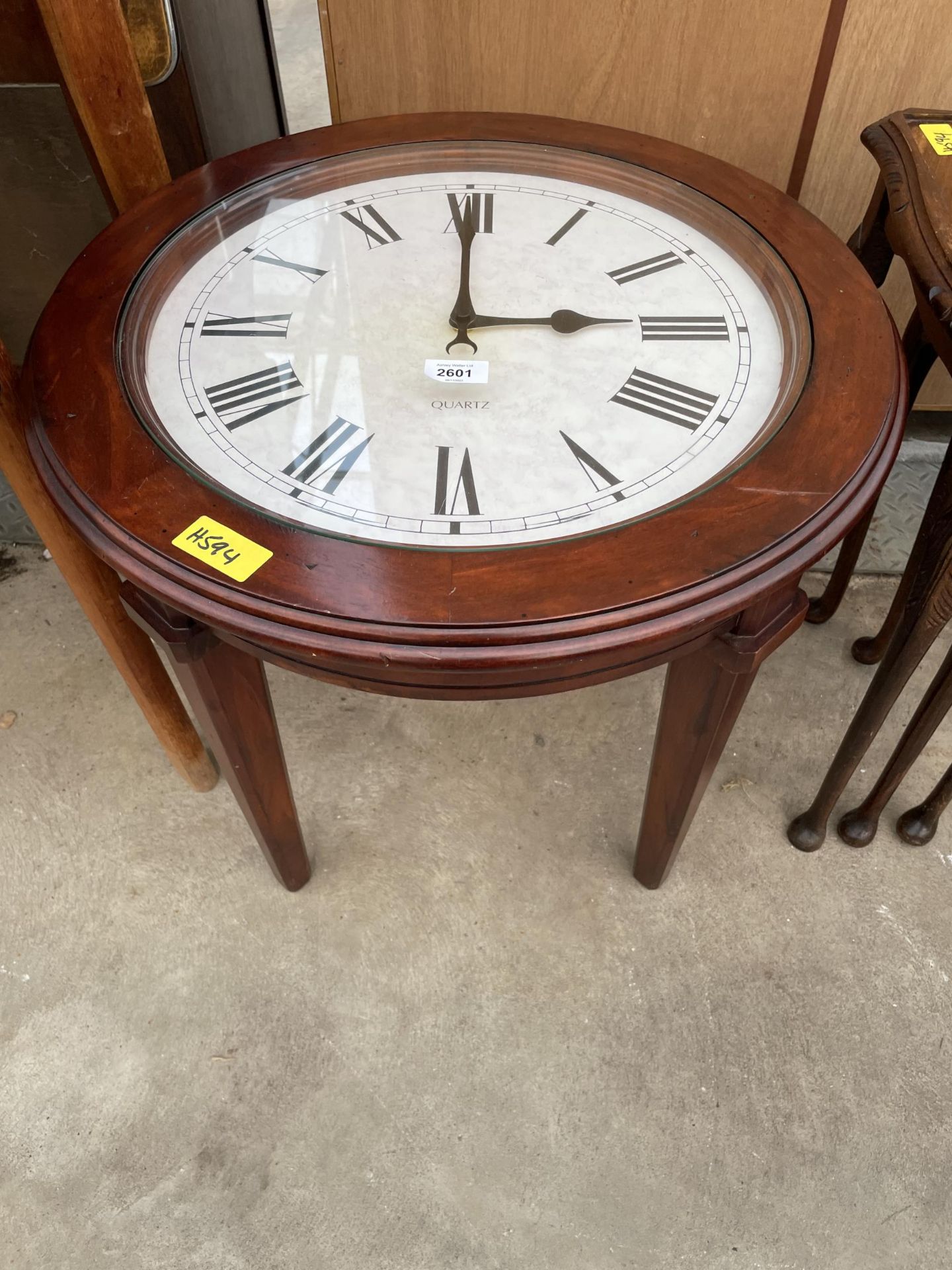 A 22" DIAMETER OCCASIONAL TABLE, THE GLASS TOP REVEALING QUARTZ CLOCK WITH ROMAN NUMERALS