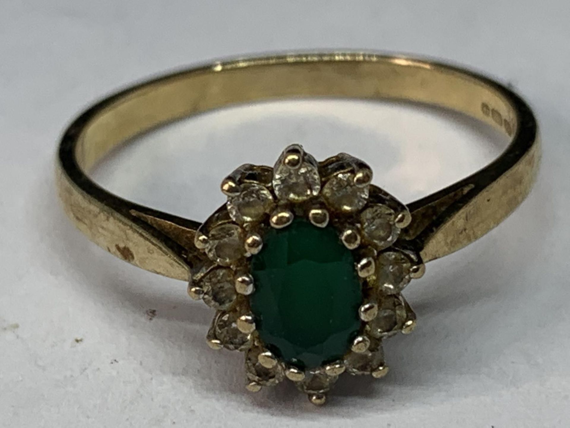 A 9 CARAT GOLD RING WITH CENTRE GREENSTONE SURROUNDED BY CUBIC ZIRCONIAS SIZE P