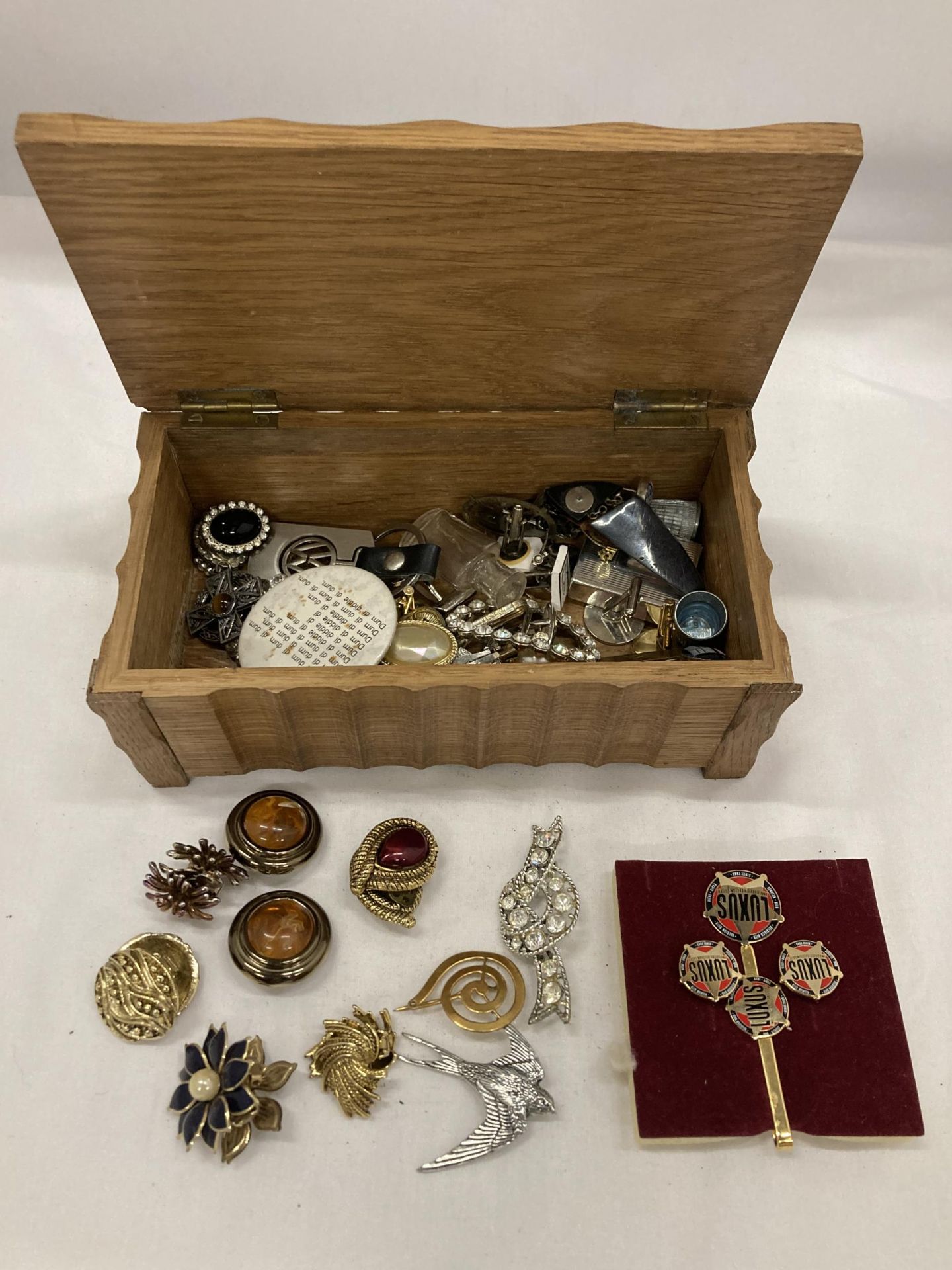 A WOODEN BOX CONTAINING A QUANTITY OF COSTUME JEWELLERY TO INCLUDE BROOCHES, BADGES, CUFFLINKS,