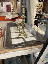 A HEAVY VINTAGE WOODEN TRAY WITH HIGH SIDES AND METAL HANDLES PLUS TWO BRASS CANDLESTICKS