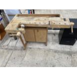 A SMALL WOODEN RJONERGS WORK BENCH WITH TWO LOWER CUPBOARDS AND TWO VICES