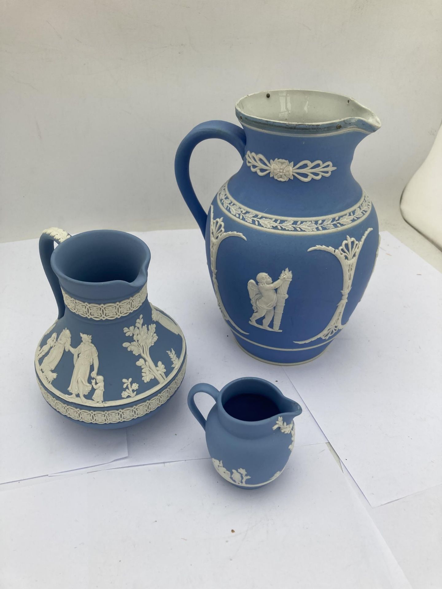 A GROUP OF THREE JASPERWARE ITEMS - TWO WEDGWOOD JUGS AND FURTHER JUG