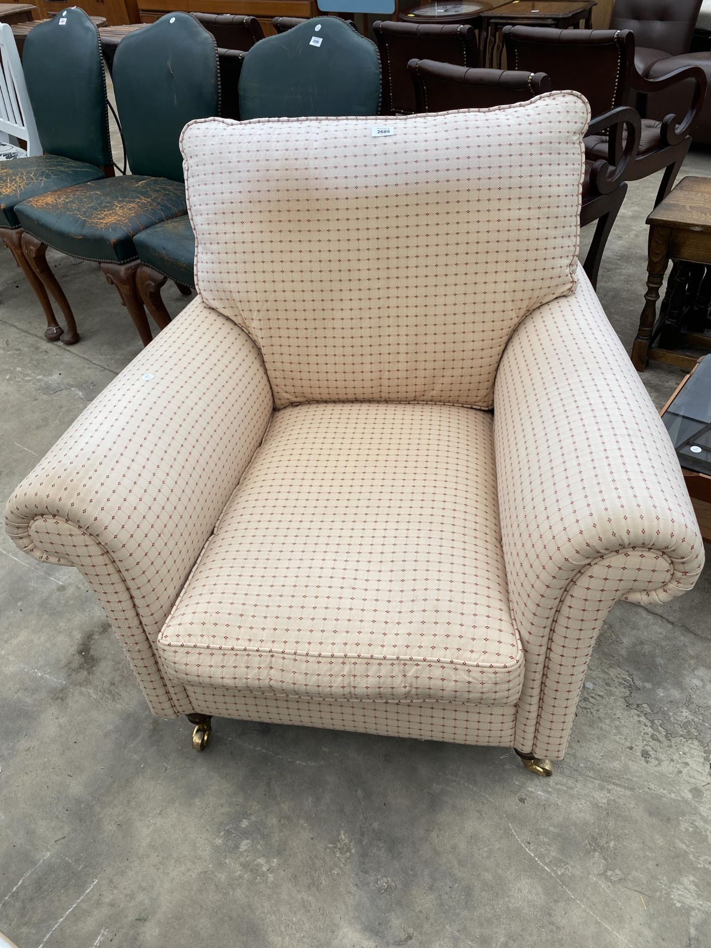 A MODERN UPHOLSTERED EASY CHAIR ON TURNED FRONT LEGS, WITH BRASS CASTERS, 36" WIDE