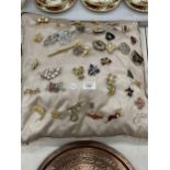 A CUSHION CONTAINING 40 COSTUME JEWELLERY BROOCHES