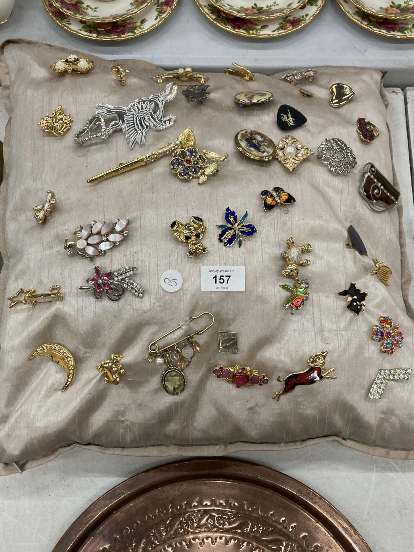 A CUSHION CONTAINING 40 COSTUME JEWELLERY BROOCHES