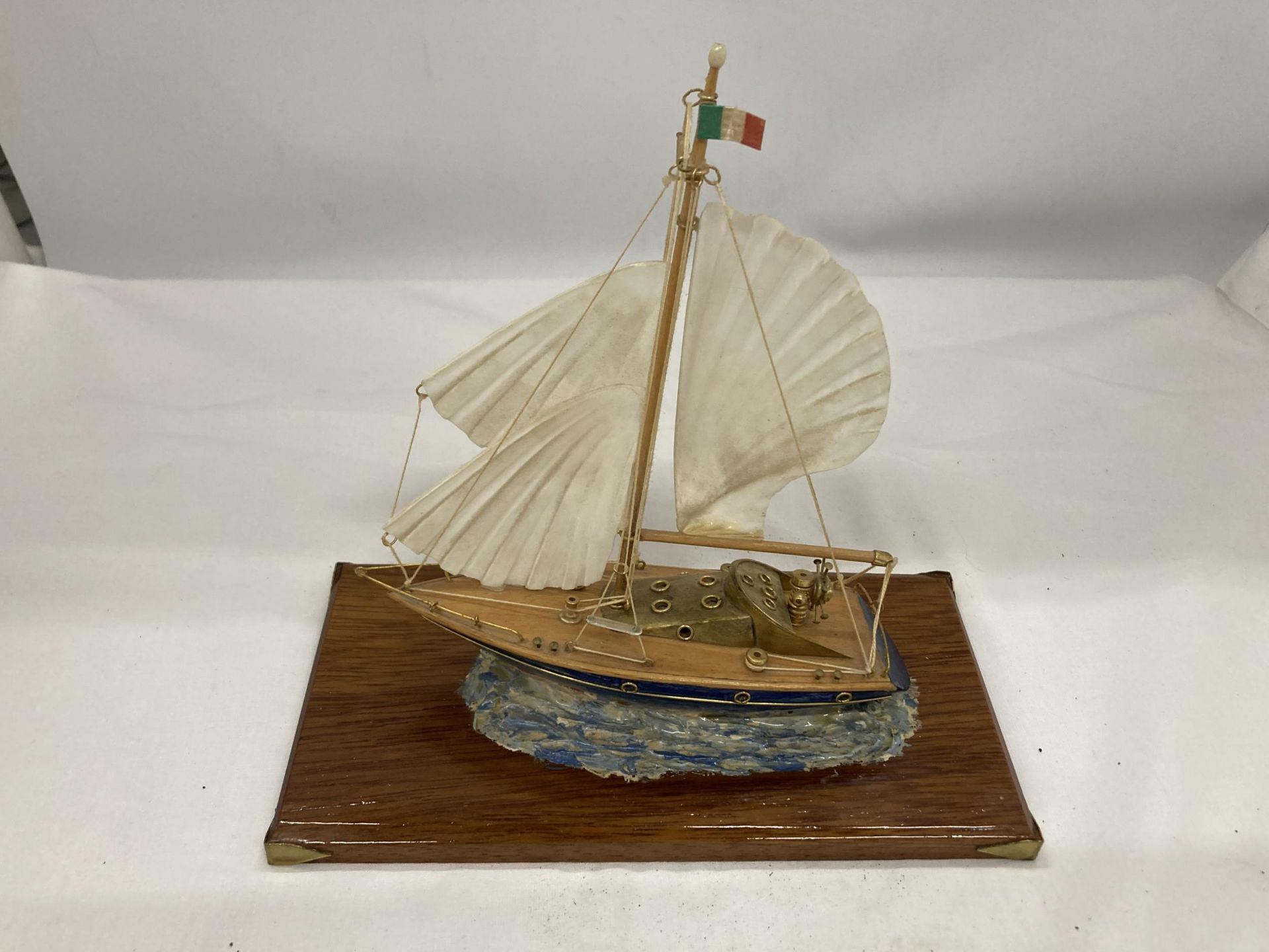 A MODEL OF A VINTAGE ITALIAN YACHT, ON A WOODEN PLINTH, WITH ENAMEL AND BRASS HULL, HEIGHT APPROX