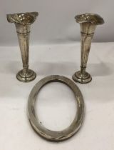 THREE HALLMARKED SILVER ITEMS - PAIR OF WALKER AND HALL BUD VASES AND AN OVAL PHOTO FRAME