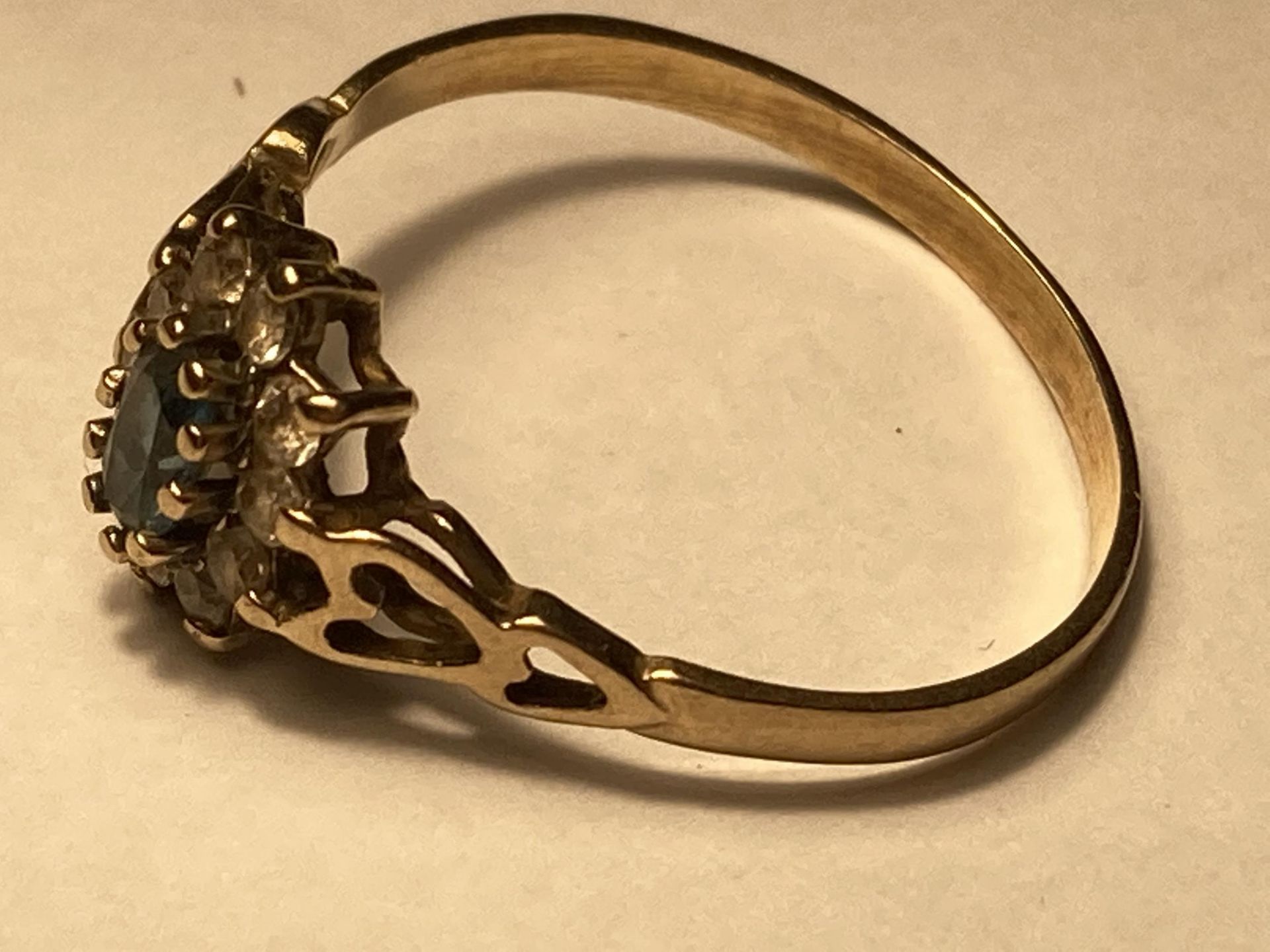 A 9 CARAT GOLD RING WITH A CENTRE BLUE TOPAZ STONE SURROUNDED BY CUBIC ZIRCONIAS SIZE O/P - Image 2 of 3