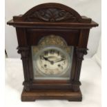 A VINTAGE CARVED OAK MANTLE CLOCK WITH PENDULUM AND KEY