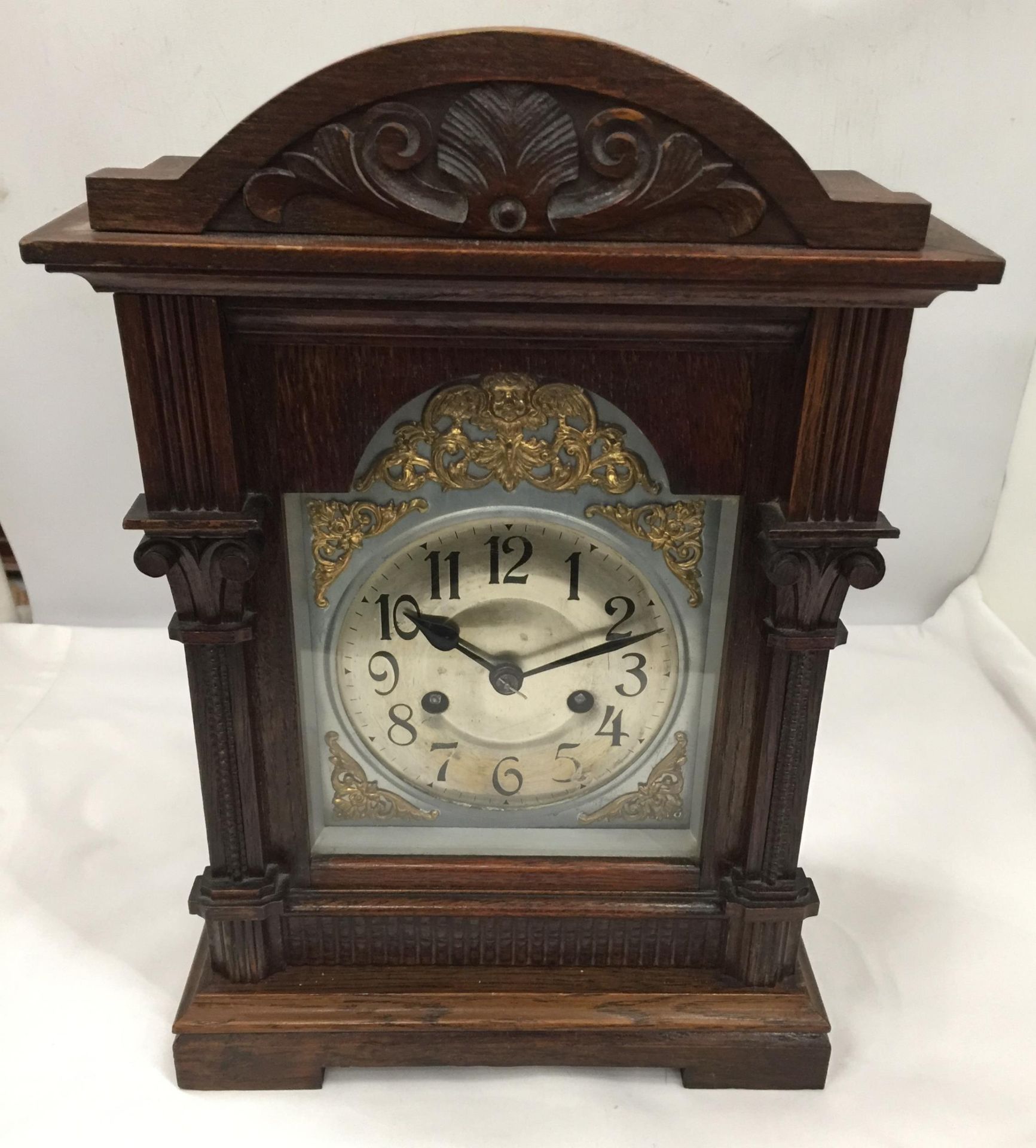 A VINTAGE CARVED OAK MANTLE CLOCK WITH PENDULUM AND KEY