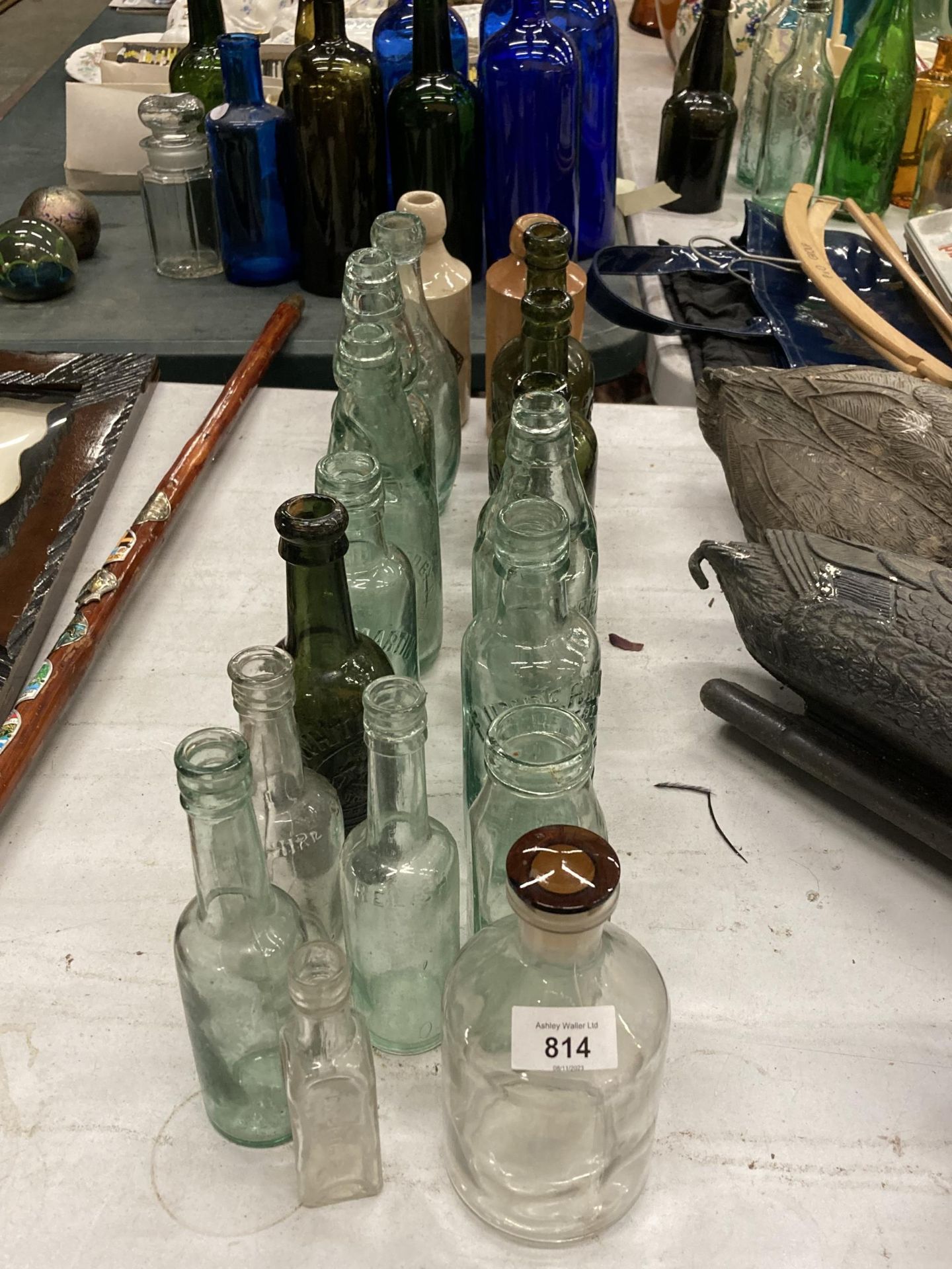 A COLLECTION OF VINTAGE GLASS BOTTLES WITH ADVERTISING ON THEM PLUS TWO STONE ONES