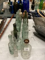 A COLLECTION OF VINTAGE GLASS BOTTLES WITH ADVERTISING ON THEM PLUS TWO STONE ONES